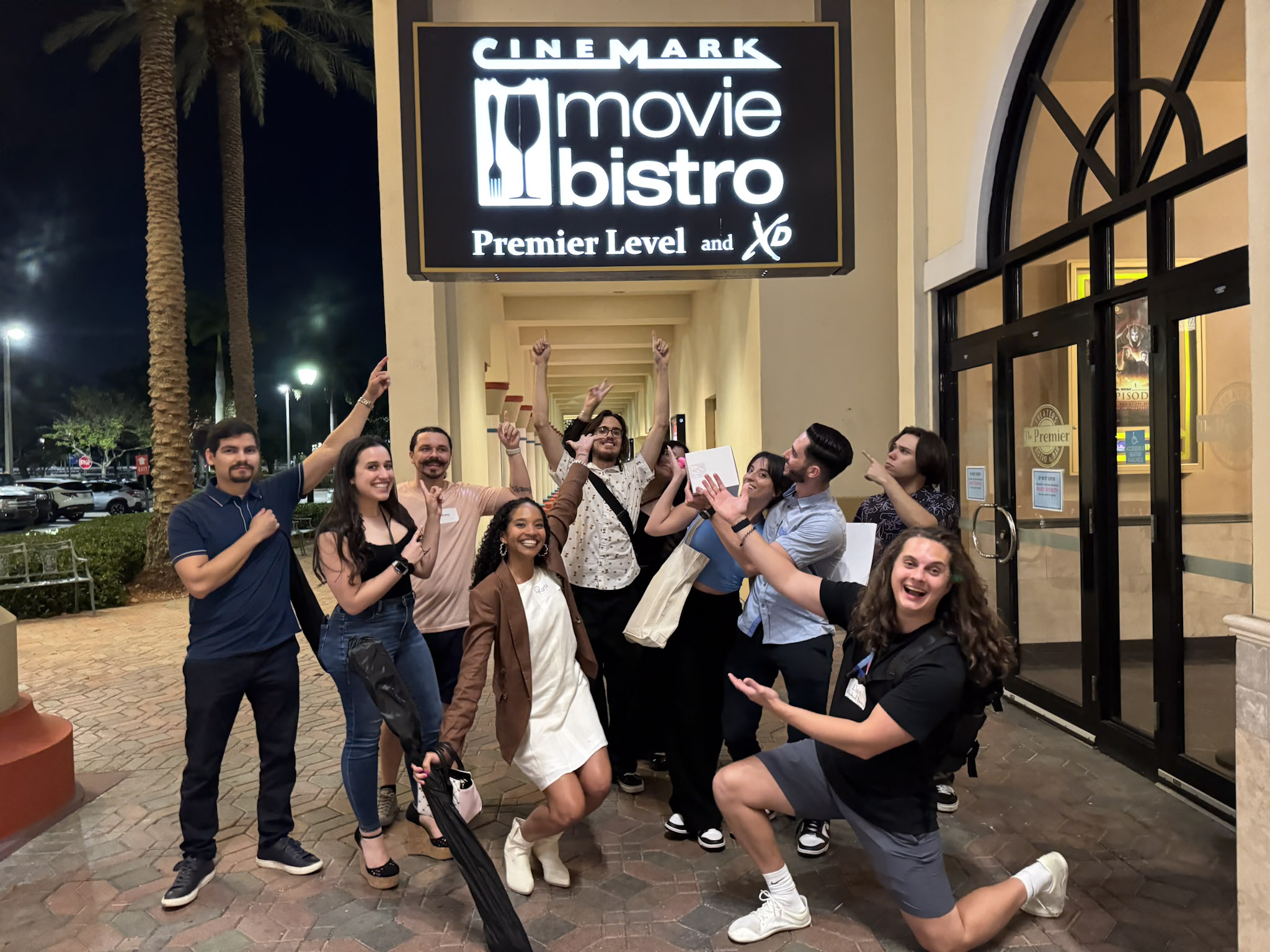 TENM event participants point outside towards the Cinemark Movie Bistro Sign.